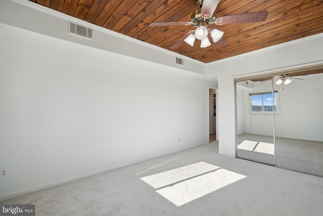 unfurnished bedroom with light carpet, crown molding, wooden ceiling, and a closet