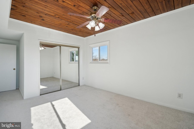 unfurnished bedroom with crown molding, ceiling fan, light carpet, wooden ceiling, and a closet