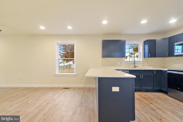 kitchen with stainless steel appliances, sink, and light hardwood / wood-style flooring