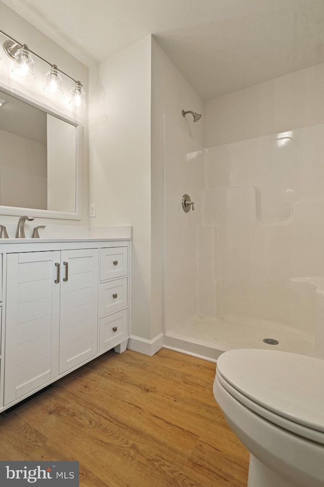 bathroom featuring toilet, a shower, vanity, and wood-type flooring