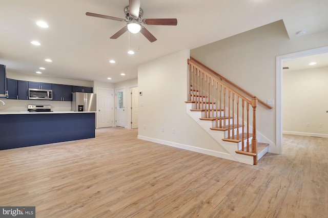 kitchen featuring appliances with stainless steel finishes, ceiling fan, a kitchen bar, light hardwood / wood-style flooring, and blue cabinets