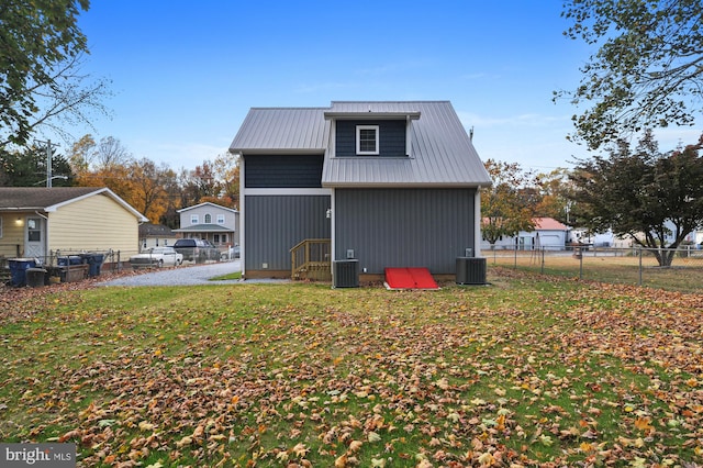 back of property with central AC unit and a lawn