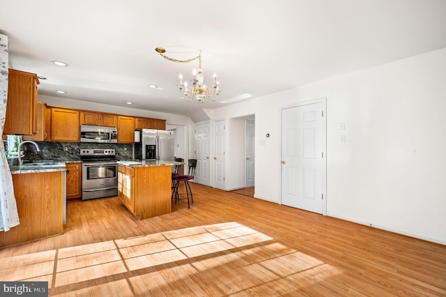 kitchen with a center island, light wood-type flooring, appliances with stainless steel finishes, and an inviting chandelier