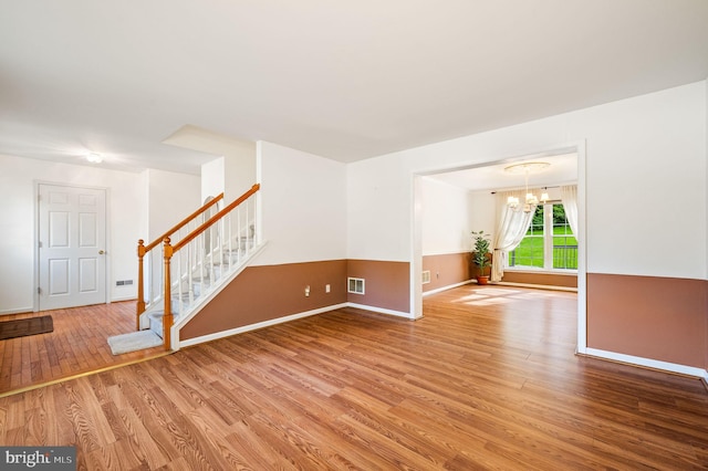 unfurnished living room with a chandelier and wood-type flooring