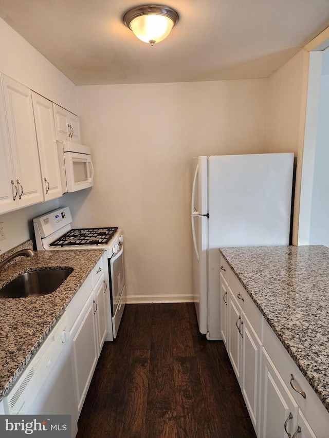 kitchen with white cabinets, stone countertops, dark wood-type flooring, sink, and white appliances