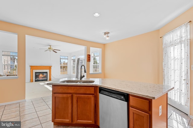 kitchen with light tile patterned flooring, sink, ceiling fan, stainless steel dishwasher, and a center island with sink