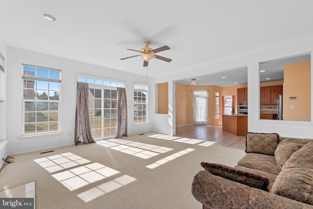 living room featuring light colored carpet, plenty of natural light, and ceiling fan