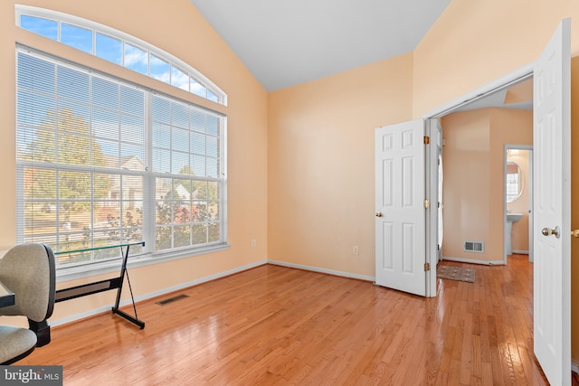 home office featuring light hardwood / wood-style floors, vaulted ceiling, and plenty of natural light