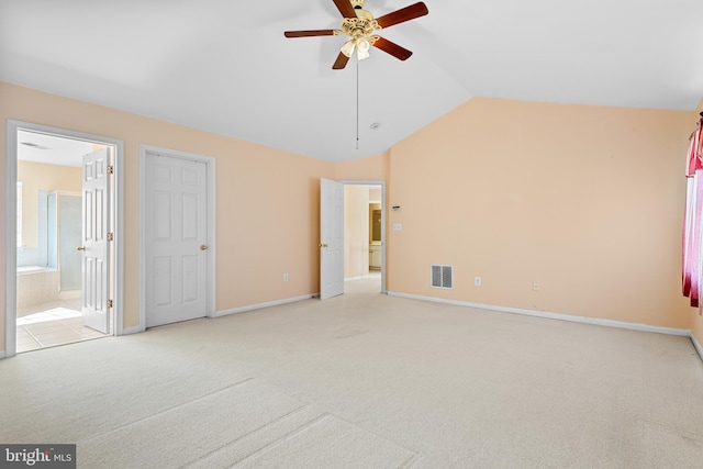 unfurnished bedroom featuring lofted ceiling, ensuite bathroom, light colored carpet, and ceiling fan