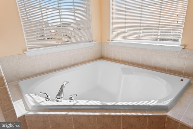 bathroom featuring a relaxing tiled tub and a healthy amount of sunlight