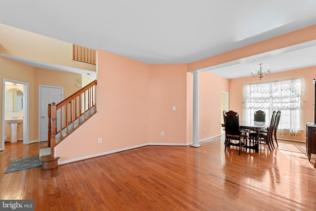 dining room featuring an inviting chandelier, sink, light wood-type flooring, and decorative columns