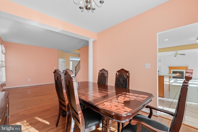 dining room featuring decorative columns, wood-type flooring, and ceiling fan with notable chandelier