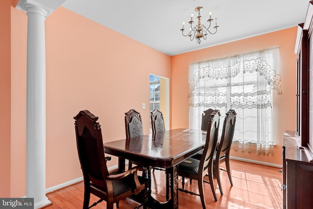 dining space featuring ornate columns, a notable chandelier, and light hardwood / wood-style flooring