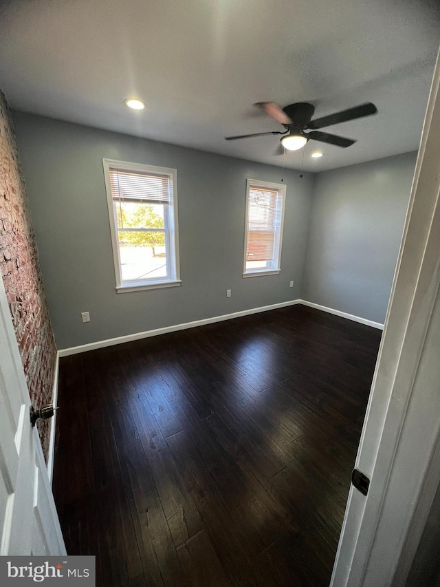 unfurnished room featuring dark wood-type flooring and ceiling fan