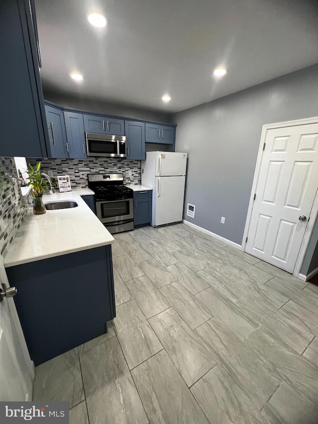 kitchen featuring backsplash, sink, blue cabinetry, and stainless steel appliances