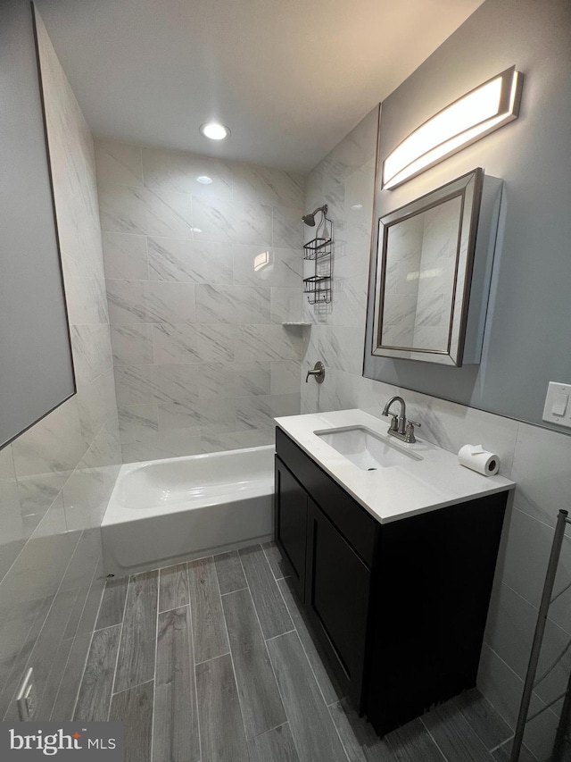 bathroom with vanity, tile walls, and tiled shower / bath combo