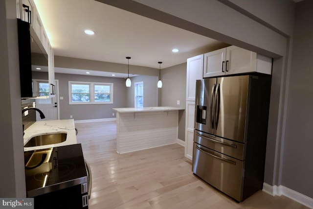 kitchen with kitchen peninsula, white cabinets, appliances with stainless steel finishes, light hardwood / wood-style flooring, and sink