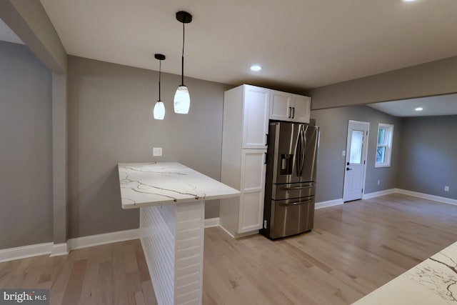 kitchen featuring kitchen peninsula, light stone countertops, stainless steel fridge with ice dispenser, light wood-type flooring, and white cabinets