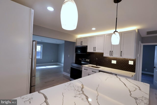 kitchen with appliances with stainless steel finishes, white cabinetry, light stone countertops, decorative light fixtures, and sink