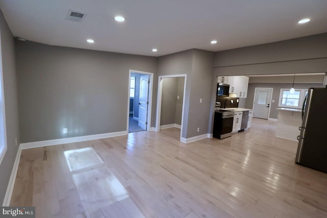 kitchen with white cabinetry, appliances with stainless steel finishes, light hardwood / wood-style flooring, and pendant lighting