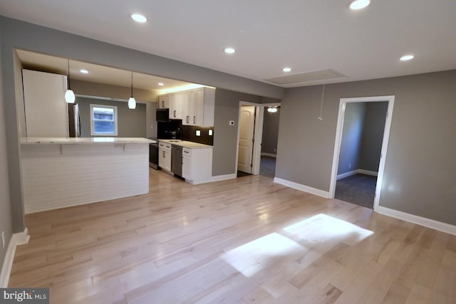 kitchen featuring kitchen peninsula, white cabinets, hanging light fixtures, appliances with stainless steel finishes, and light hardwood / wood-style floors