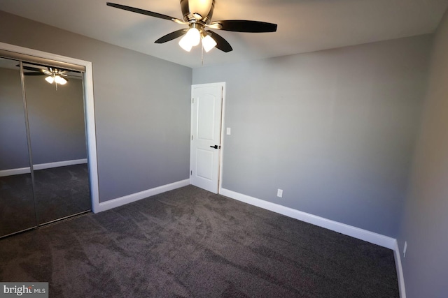 unfurnished bedroom featuring a closet, dark carpet, and ceiling fan