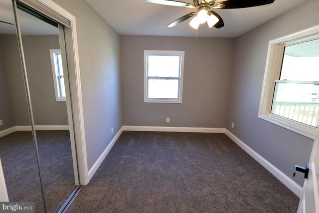 spare room featuring ceiling fan and dark colored carpet