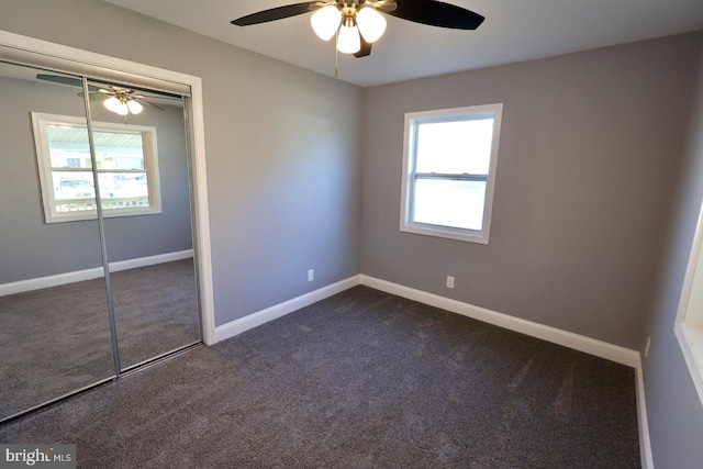 unfurnished bedroom featuring a closet, dark carpet, and ceiling fan