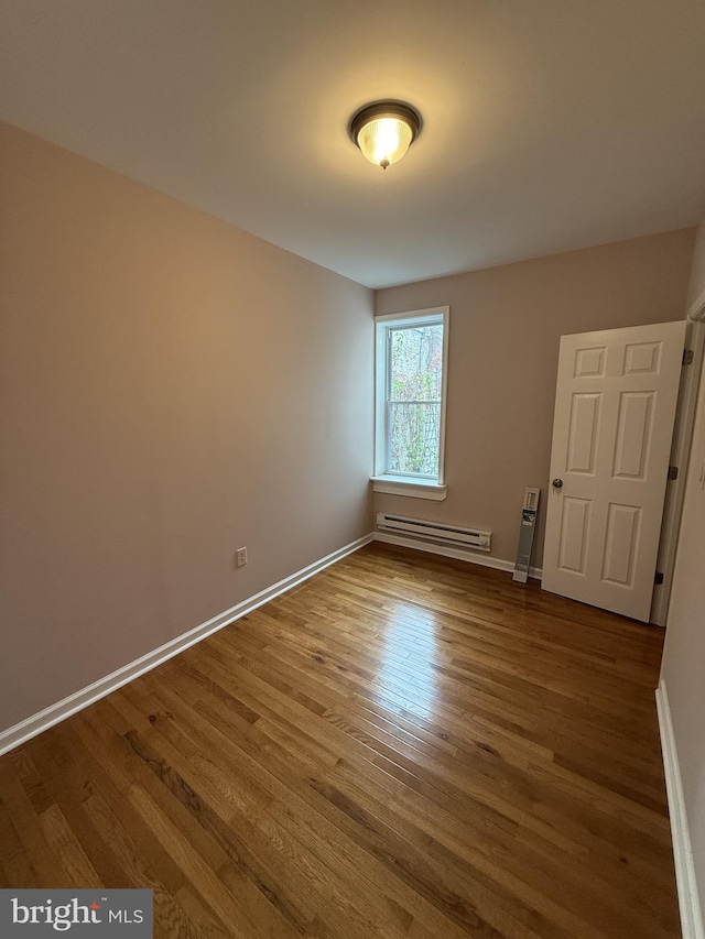 spare room with a baseboard radiator and hardwood / wood-style flooring