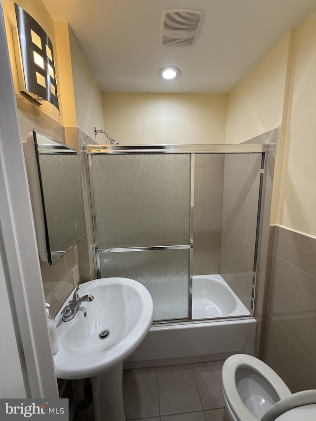 full bathroom with sink, bath / shower combo with glass door, toilet, and tile patterned flooring