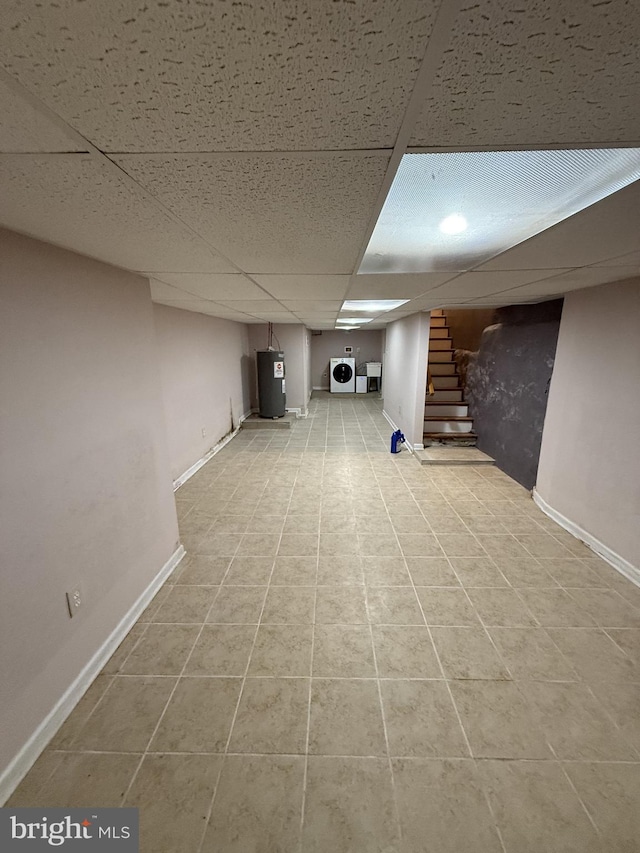 basement with a paneled ceiling, washer / clothes dryer, light tile patterned flooring, and water heater