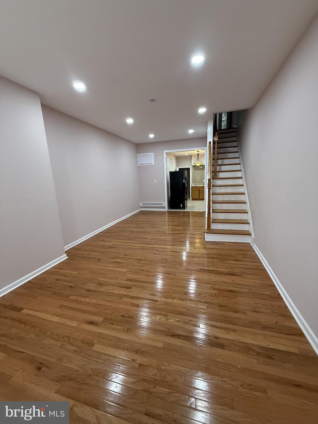 unfurnished living room featuring a baseboard heating unit and hardwood / wood-style flooring