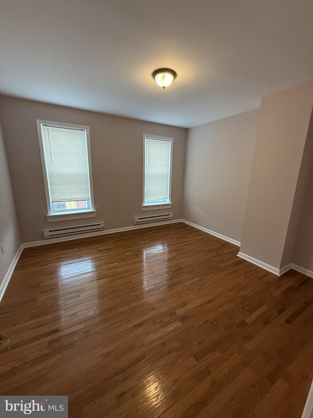 spare room with a baseboard heating unit and dark hardwood / wood-style floors