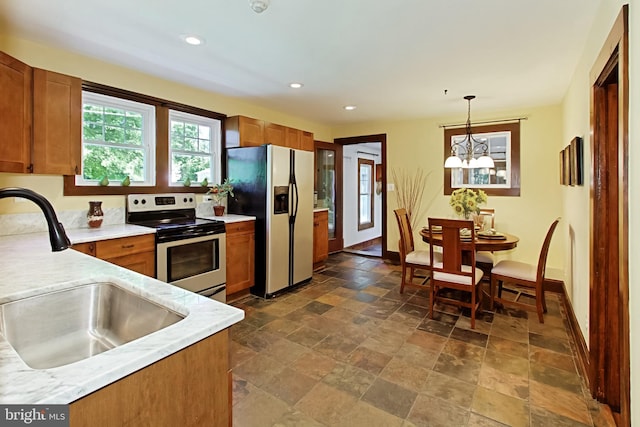 kitchen with sink, appliances with stainless steel finishes, hanging light fixtures, and a chandelier