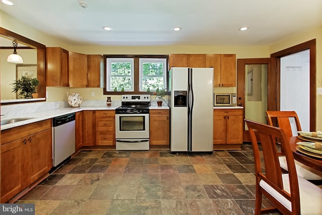 kitchen with appliances with stainless steel finishes, sink, and hanging light fixtures