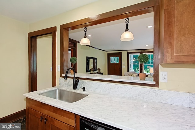 kitchen with sink, light stone countertops, hanging light fixtures, and crown molding