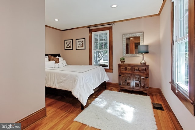 bedroom featuring light hardwood / wood-style floors, multiple windows, and ornamental molding