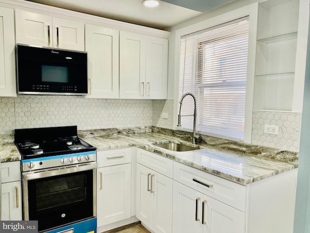 kitchen featuring light stone countertops, stainless steel electric stove, white cabinets, and sink