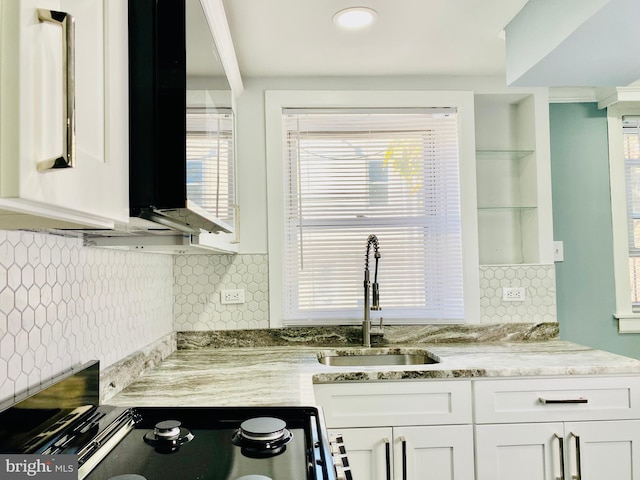 kitchen featuring light stone countertops, white cabinetry, backsplash, and sink