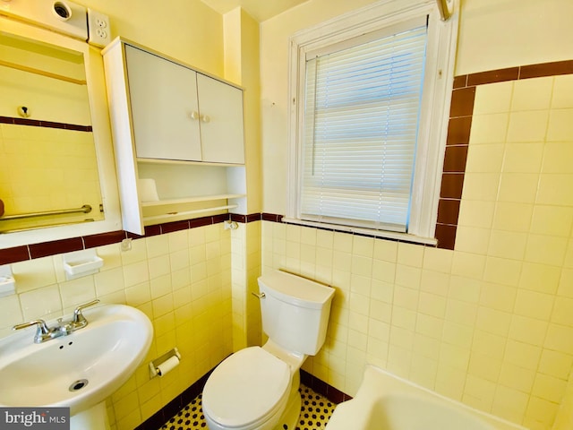 bathroom featuring sink, tile walls, and toilet