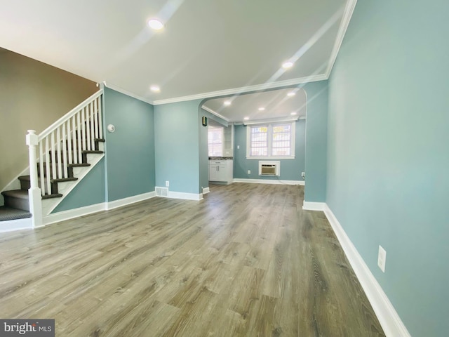 unfurnished living room featuring crown molding, light hardwood / wood-style flooring, and a wall mounted air conditioner