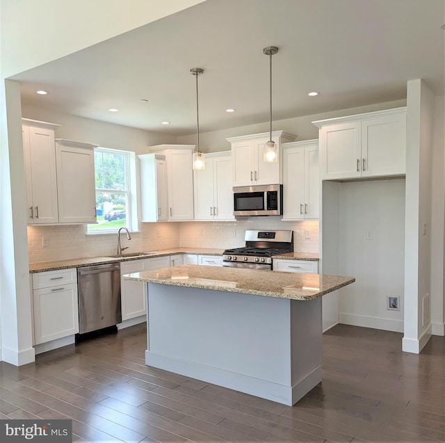 kitchen featuring a center island, hanging light fixtures, stainless steel appliances, and white cabinetry