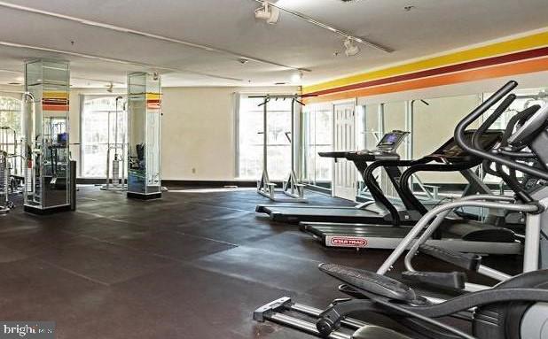 gym with rail lighting and a healthy amount of sunlight