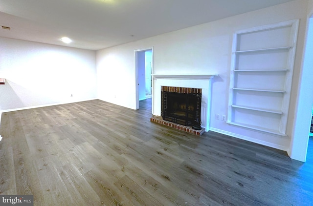 unfurnished living room with built in shelves, a fireplace, and wood-type flooring