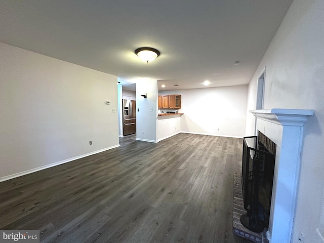 unfurnished living room featuring dark wood-type flooring and a brick fireplace