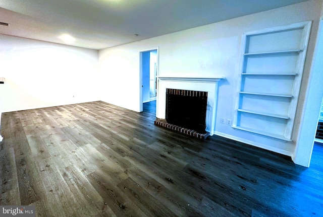 unfurnished living room with built in features and dark wood-type flooring