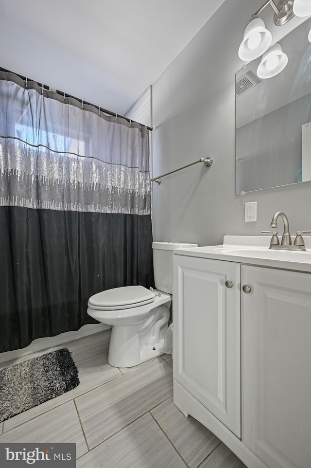 bathroom with toilet, walk in shower, and vanity