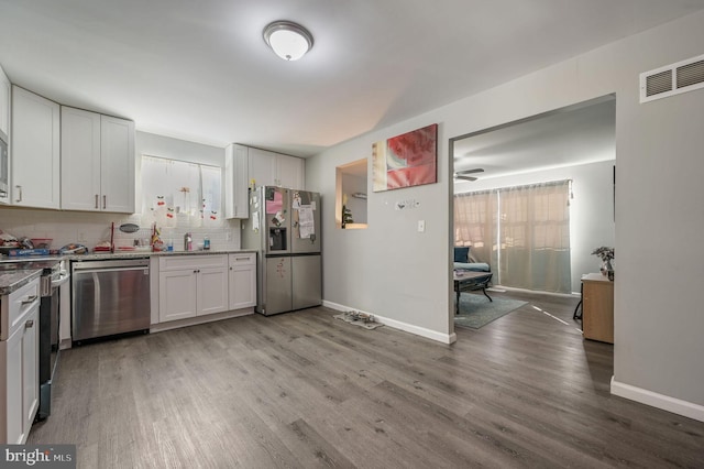 kitchen with appliances with stainless steel finishes, sink, backsplash, white cabinetry, and light hardwood / wood-style floors