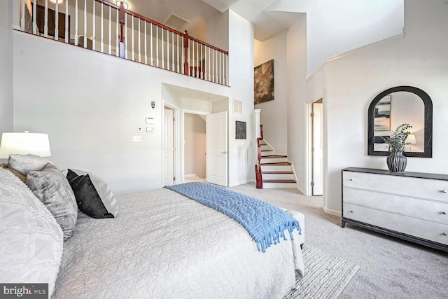 carpeted bedroom with a towering ceiling and ornamental molding