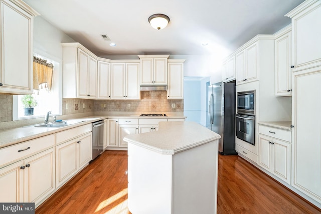 kitchen with sink, hardwood / wood-style floors, stainless steel appliances, and a kitchen island